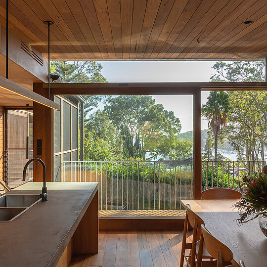 Interior photograph of Bayview Tree House by The kitchen offers prospect through spotted gum eucalypts toward Pittwater and Lion Island. Photographer: Luke Shadbolt