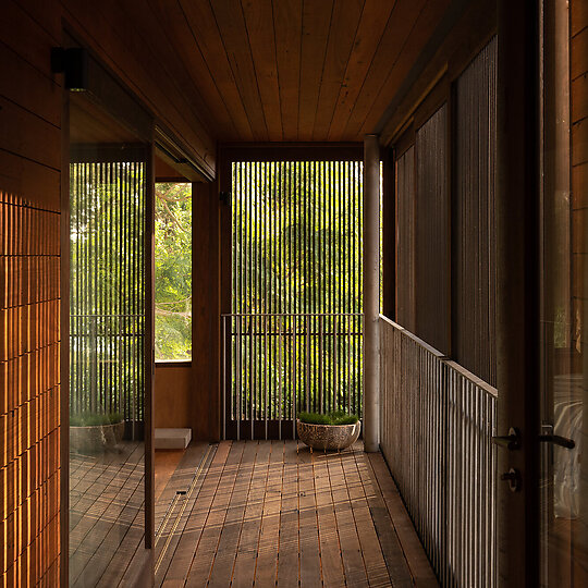 Interior photograph of Bayview Tree House by The first floor balcony, with sliding timber battens allow for circulation and light, simultaneously connecting the surrounding bushland. Photographer: Luke Shadbolt